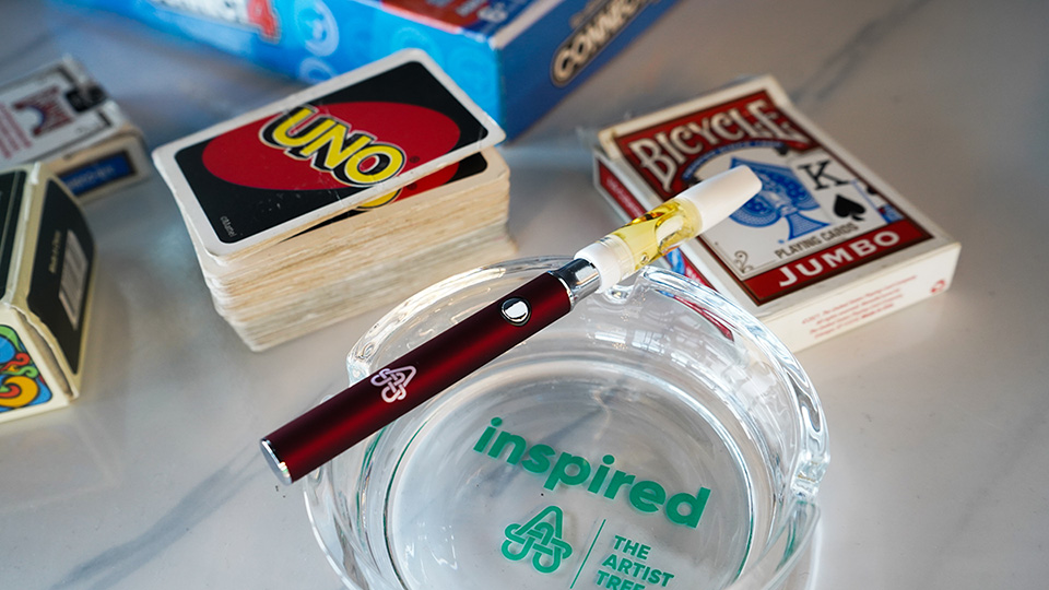 Vape pen in ashtray with playing cards